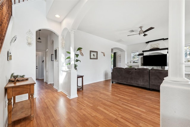 living area with light wood-type flooring, decorative columns, and arched walkways