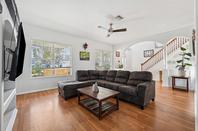 living area with stairway, visible vents, arched walkways, and wood finished floors