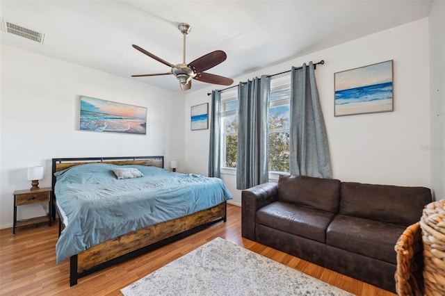 bedroom with light wood-style floors, visible vents, and ceiling fan