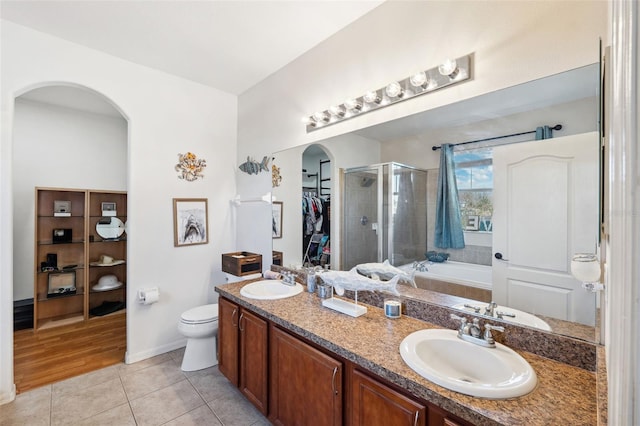 bathroom featuring double vanity, a stall shower, a sink, and tile patterned floors