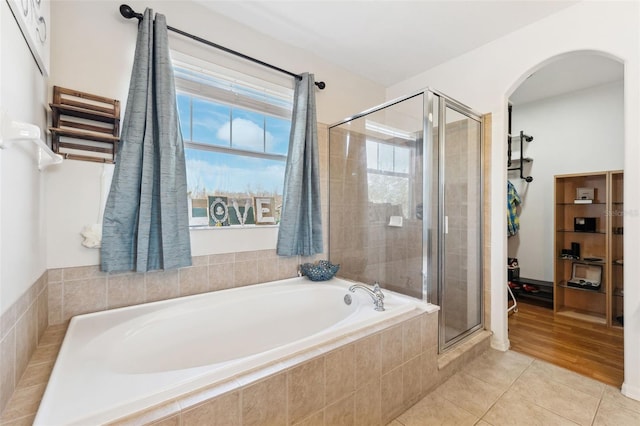 bathroom with a shower stall, a bath, and tile patterned floors