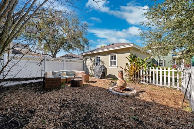 back of house with a fenced backyard, an outdoor living space, and stucco siding