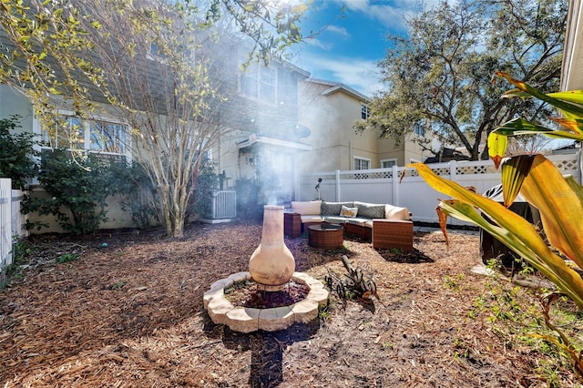 view of yard featuring an outdoor living space with a fire pit, a fenced backyard, and central AC unit