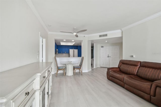 living room featuring ornamental molding, light hardwood / wood-style floors, and ceiling fan