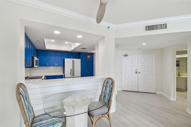 dining space with crown molding, ceiling fan, a raised ceiling, and light wood-type flooring