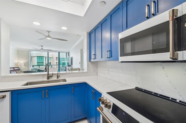 kitchen with electric stove, sink, light stone counters, and blue cabinetry