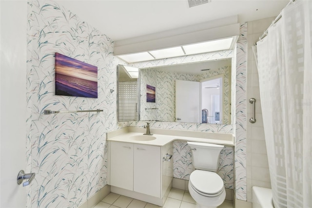 full bathroom with shower / tub combo with curtain, tile patterned flooring, a skylight, vanity, and toilet