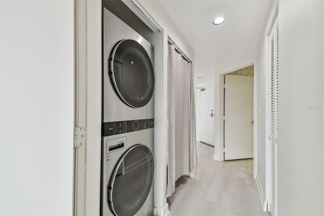 laundry room with stacked washer / dryer and light hardwood / wood-style floors