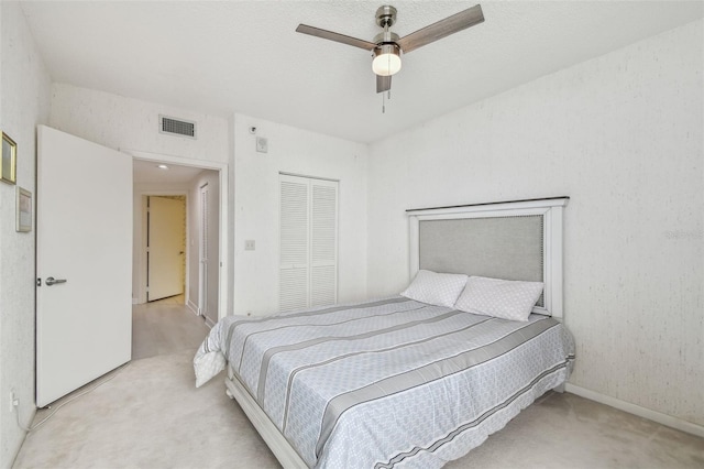 carpeted bedroom featuring ceiling fan, a closet, and a textured ceiling