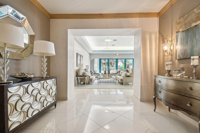 tiled entrance foyer with crown molding and a tray ceiling