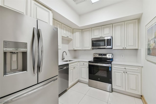 kitchen with sink, light tile patterned floors, and stainless steel appliances