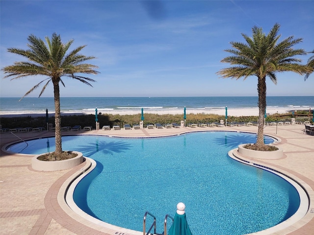 view of pool featuring a water view and a view of the beach