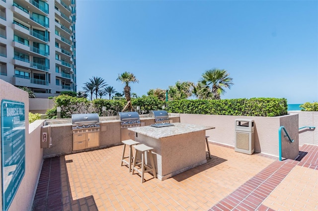 view of patio / terrace with area for grilling, a grill, an outdoor bar, and a water view