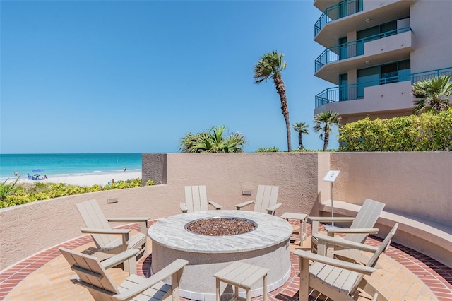 view of patio with a water view, a beach view, and a fire pit