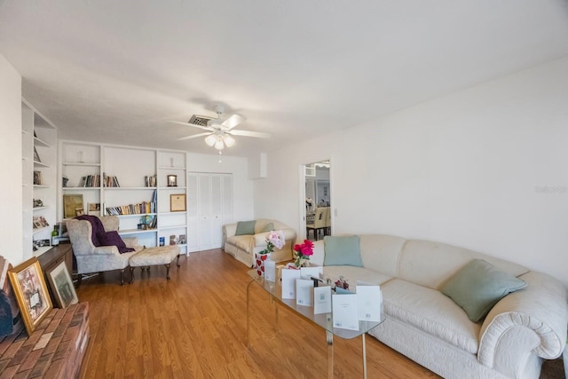 living room featuring hardwood / wood-style flooring, built in features, and ceiling fan