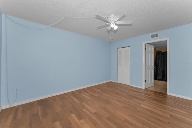 unfurnished bedroom with ceiling fan, light hardwood / wood-style flooring, a closet, and a textured ceiling