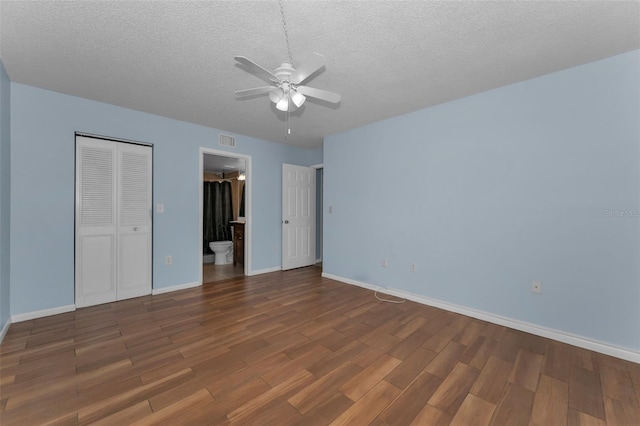 unfurnished bedroom featuring connected bathroom, ceiling fan, dark wood-type flooring, a textured ceiling, and a closet