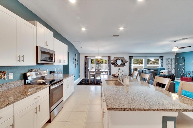 kitchen featuring appliances with stainless steel finishes, decorative light fixtures, sink, a kitchen breakfast bar, and a large island