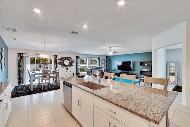 kitchen featuring sink, decorative light fixtures, a center island with sink, dishwasher, and white cabinets