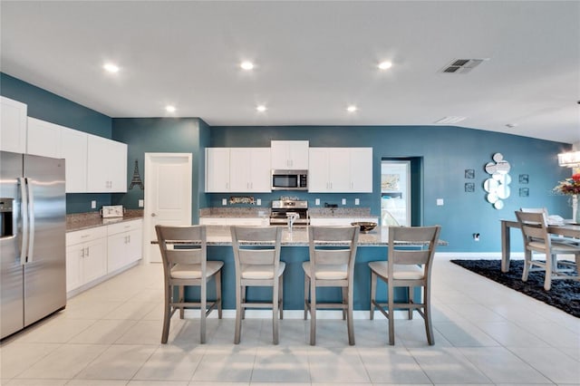 kitchen featuring stainless steel appliances, a breakfast bar area, a center island with sink, and white cabinets