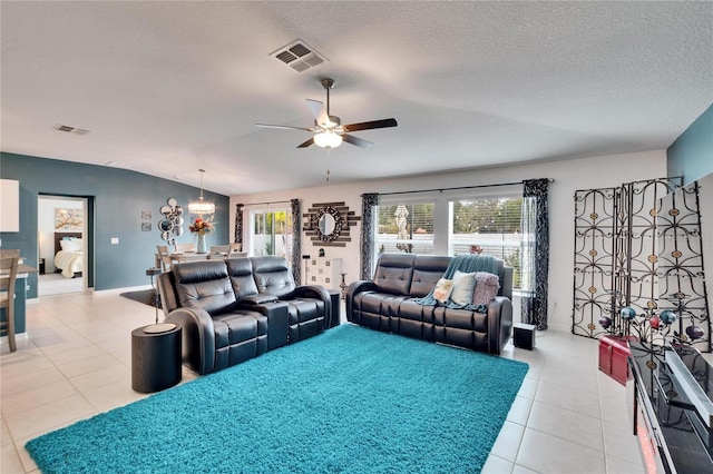 living room with ceiling fan, lofted ceiling, a textured ceiling, and light tile patterned floors