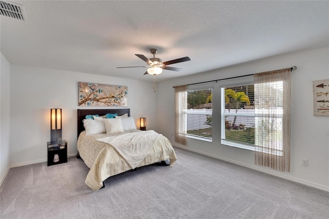 carpeted bedroom featuring ceiling fan and a textured ceiling