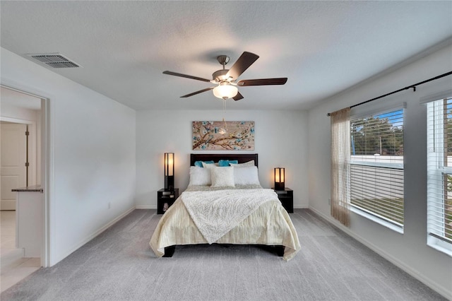 bedroom with light carpet, ceiling fan, and a textured ceiling