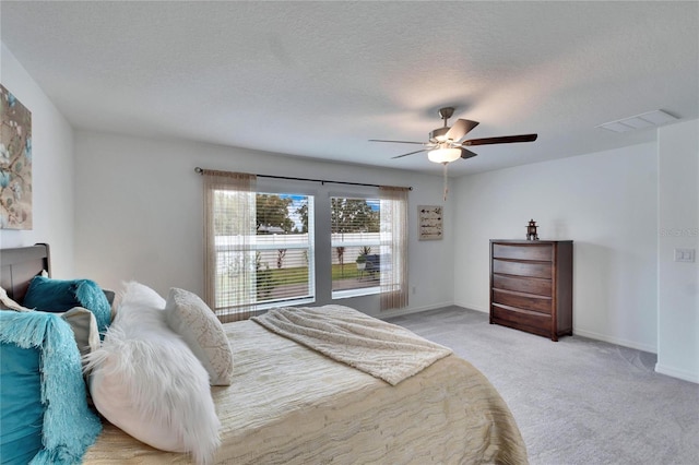 carpeted bedroom featuring ceiling fan and a textured ceiling