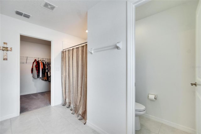 bathroom featuring walk in shower, toilet, and tile patterned flooring