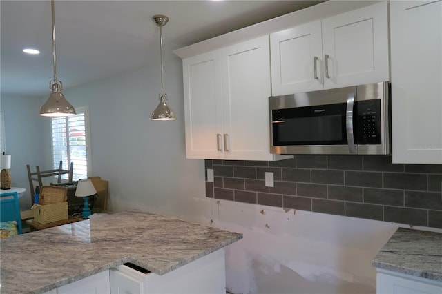 kitchen with white cabinetry, decorative backsplash, and decorative light fixtures