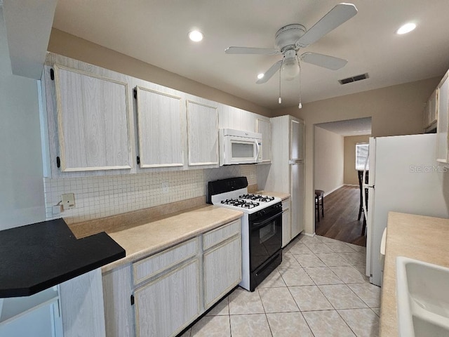 kitchen with white appliances, light tile patterned floors, sink, and backsplash