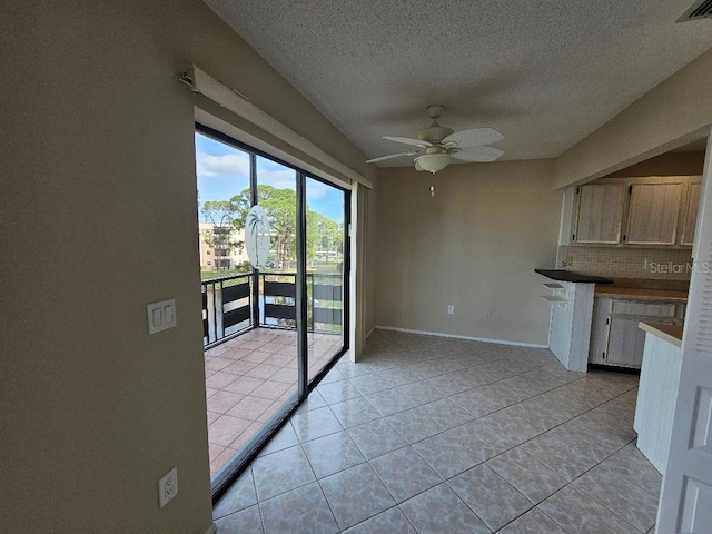 unfurnished dining area featuring ceiling fan, a textured ceiling, and light tile patterned floors