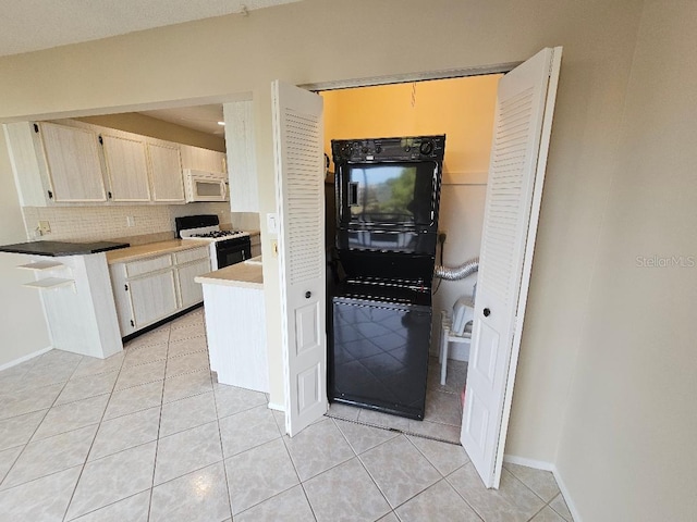 kitchen with light tile patterned floors, backsplash, and gas range oven