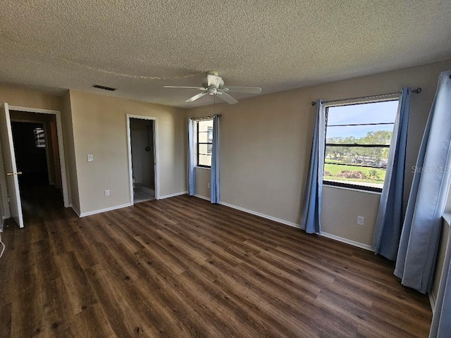 unfurnished bedroom with ceiling fan, a spacious closet, and a textured ceiling