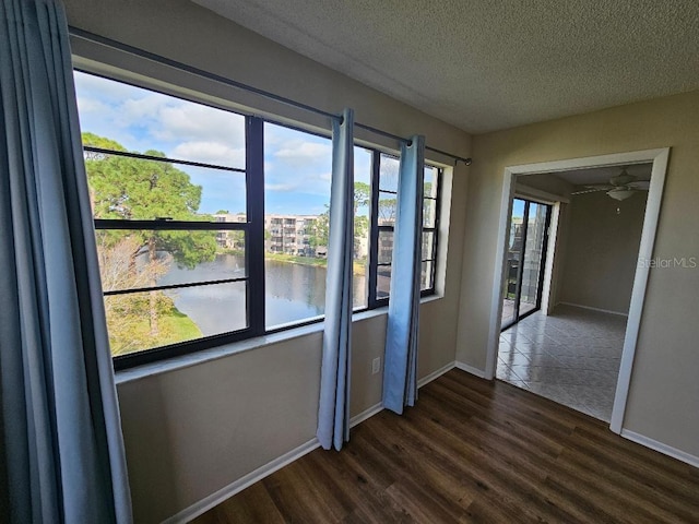 spare room featuring a water view, dark hardwood / wood-style flooring, and a textured ceiling