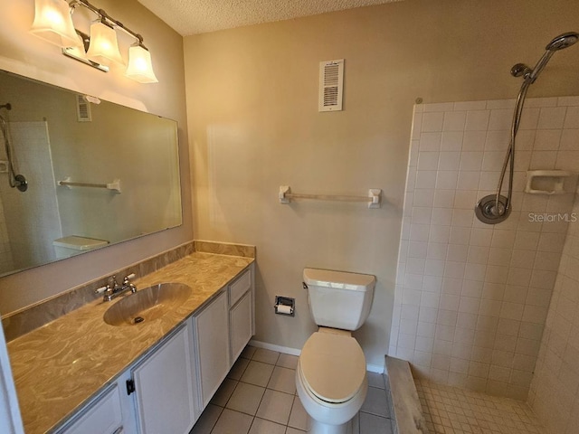 bathroom with tiled shower, toilet, a textured ceiling, vanity, and tile patterned flooring