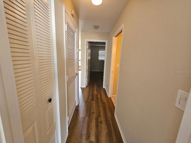 hallway with dark wood-type flooring and a textured ceiling