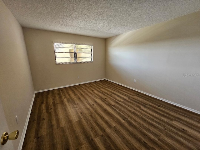 spare room featuring dark wood-type flooring and a textured ceiling