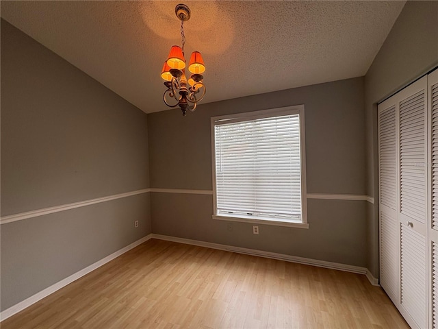 interior space featuring a textured ceiling, light hardwood / wood-style flooring, and a chandelier