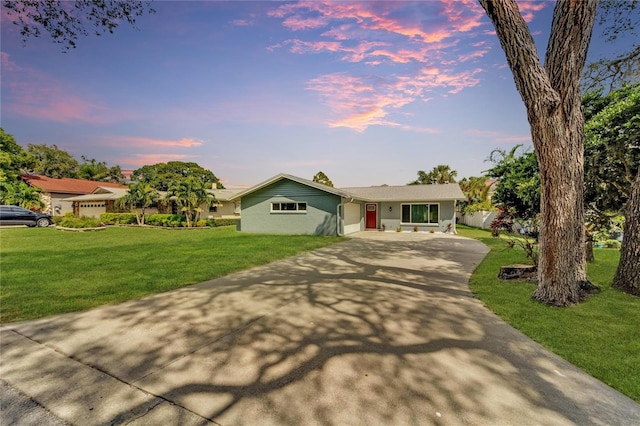 ranch-style house with a garage and a lawn