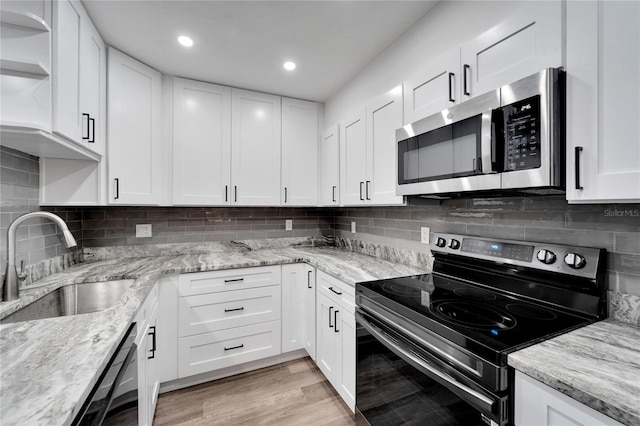 kitchen with white cabinets, light stone countertops, sink, and range with electric stovetop