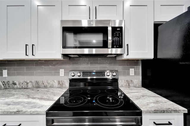 kitchen featuring tasteful backsplash, light stone countertops, stainless steel appliances, and white cabinets