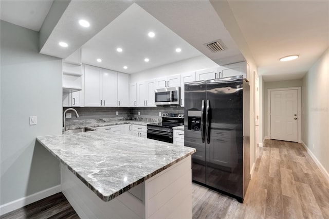 kitchen with sink, kitchen peninsula, stainless steel appliances, light stone countertops, and white cabinets