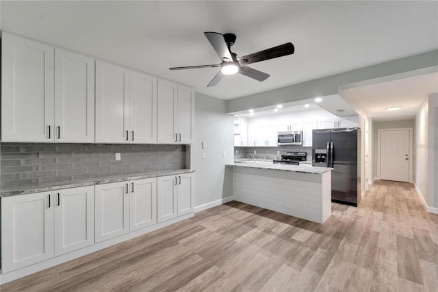 kitchen featuring light stone countertops, kitchen peninsula, white cabinets, and appliances with stainless steel finishes