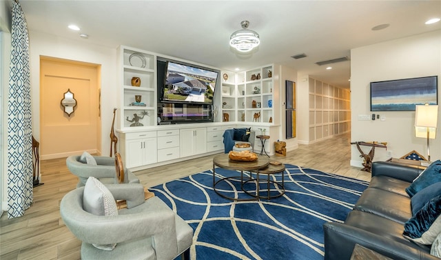 living room with light wood-type flooring and built in shelves