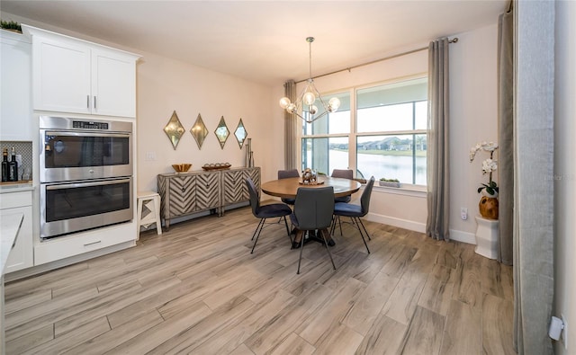 dining room with a water view, a chandelier, and light hardwood / wood-style floors