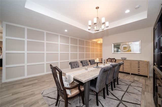 dining space featuring a notable chandelier, wood-type flooring, and a raised ceiling