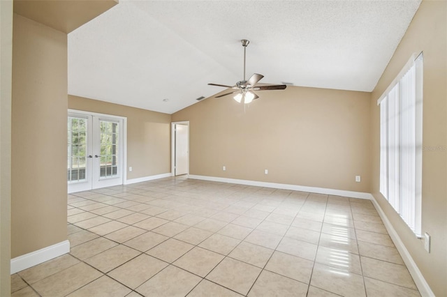 empty room with lofted ceiling, light tile patterned floors, ceiling fan, and french doors