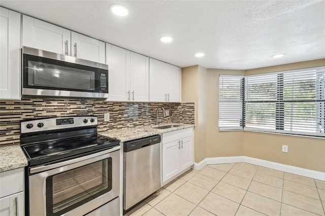 kitchen featuring white cabinetry, stainless steel appliances, sink, and light stone counters