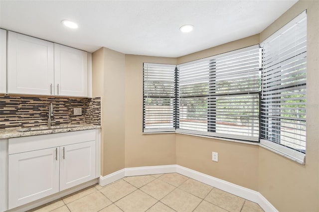 kitchen featuring white cabinets, light tile patterned floors, sink, and backsplash